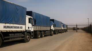 شاحنات مساعدات إنسانية متوقفة عند معبر مغلق على حدود قطاع غزة في ظل أزمة إنسانية خانقة.